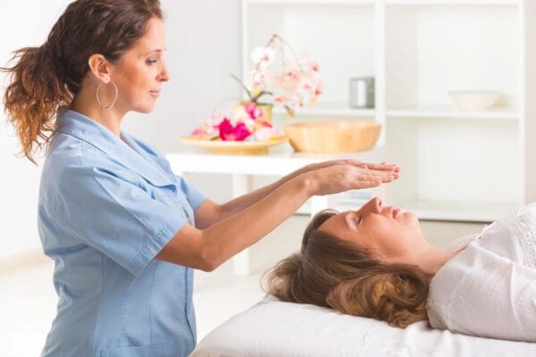 A woman is getting reiki treatment from an esthetician.