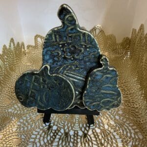 A blue ceramic sculpture sitting on top of a gold doily.