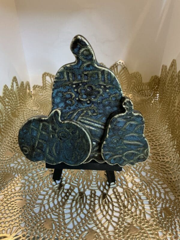 A blue ceramic sculpture sitting on top of a gold doily.