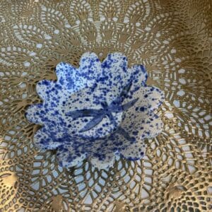 A blue and white bowl sitting on top of a lace doily.