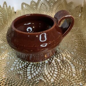 A brown cup sitting on top of a gold doily.
