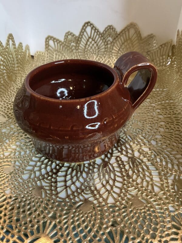 A brown cup sitting on top of a gold doily.