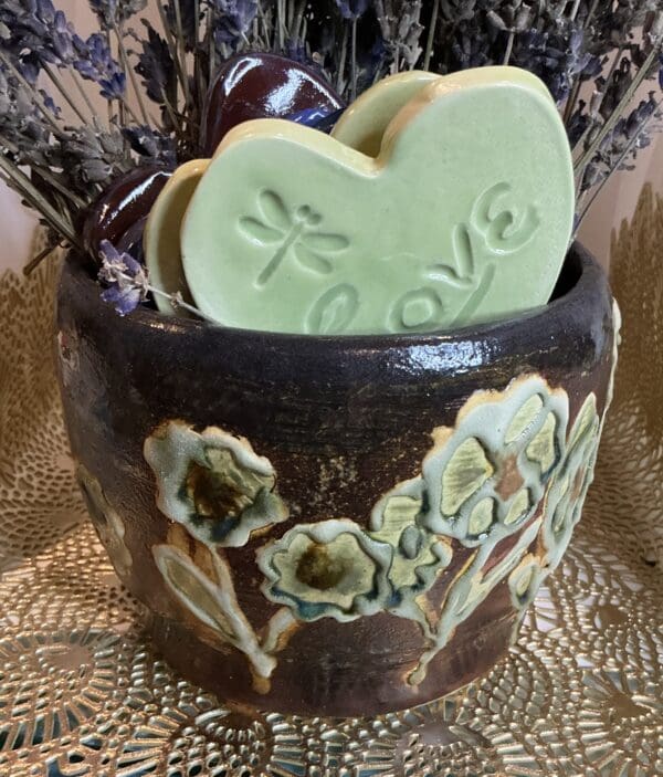 A brown vase with some green cookies in it