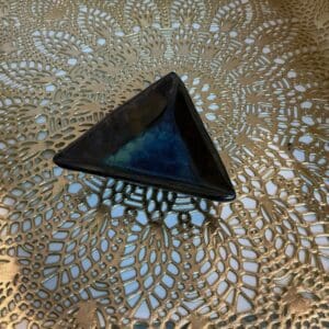 A triangle shaped object sitting on top of a lace doily.