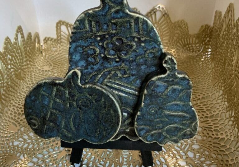 A blue ceramic sculpture sitting on top of a gold doily.