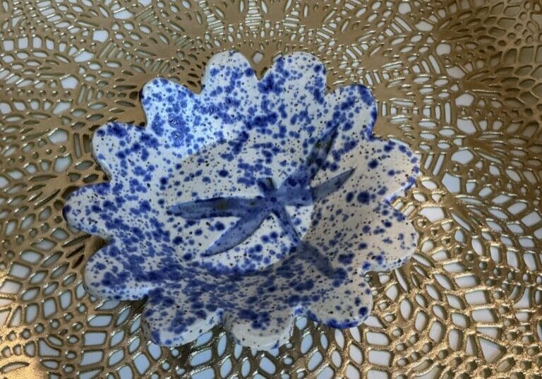 A blue and white bowl sitting on top of a lace doily.