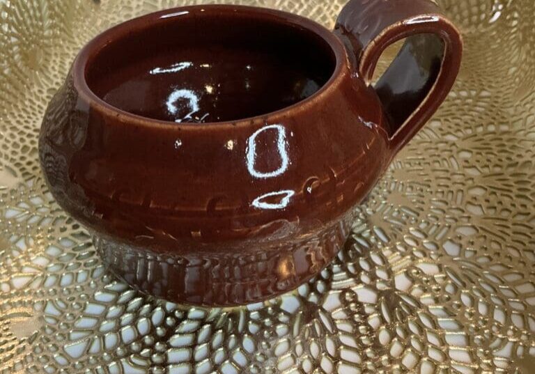 A brown cup sitting on top of a gold doily.