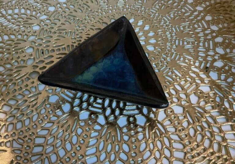 A triangle shaped object sitting on top of a lace doily.