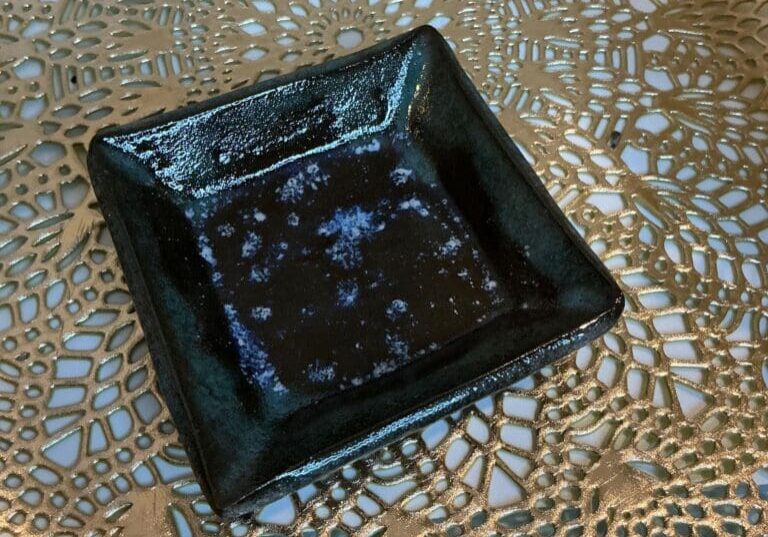 A black square plate sitting on top of a table.