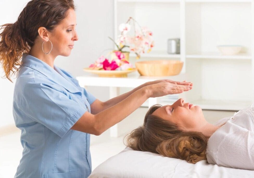 A woman is getting reiki treatment from an esthetician.